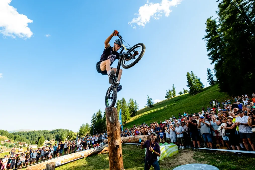 Photo de la coupe de france de VTT Trial, ou l'on voit un cycliste sur le haut d'un tronc, dans le parcours