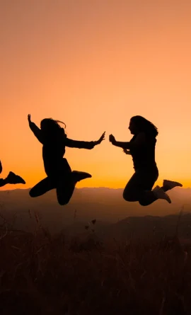 Silhouettes d'une famille sautant devant un coucher de soleil