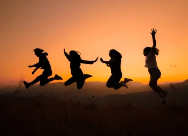Silhouettes d'une famille sautant devant un coucher de soleil